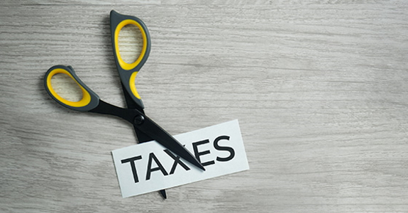 Photo of scissors cutting the printed word "TAXES"