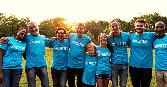 Group of smiling people in blue shirts that say, "VOLUNTEER"