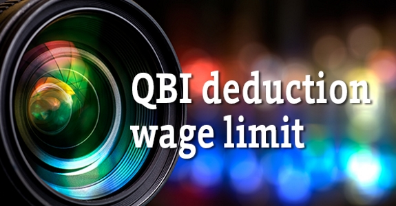 Photo of camera lens with text "QBI deduction wage limit"