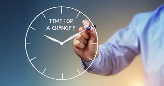 Businessman's arm drawing clock with words "TIME FOR A CHANGE?"