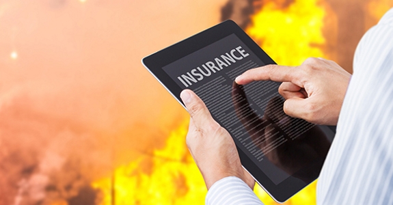 Man pointing at insurance wording on tablet with fire background