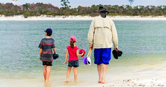 Older person on beach with young children.