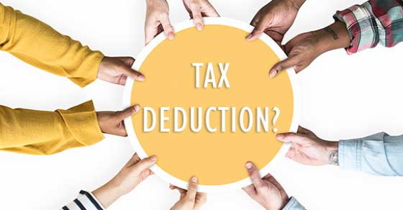 Hands of four people holding a circular object with "TAX DEDUCTION?" written on it