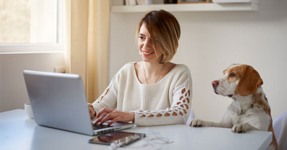 Woman and dog looking at screen of laptop