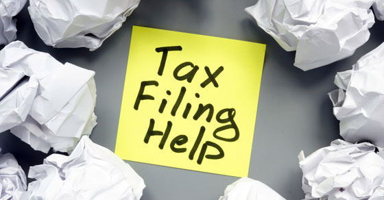 Sticky note, with "Tax Filing Help" written on it, surrounded by crumpled sheets of paper