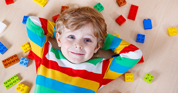 Child lying on floor with hands behind head and surrounded by building blocks