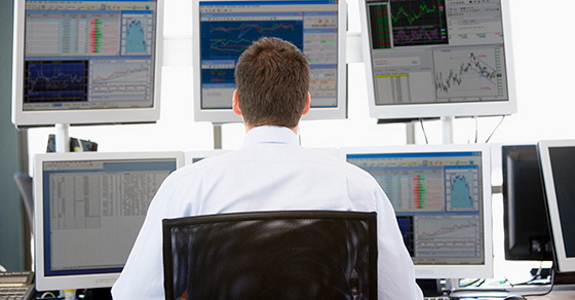 Person sitting in office chair, looking at several computer monitors